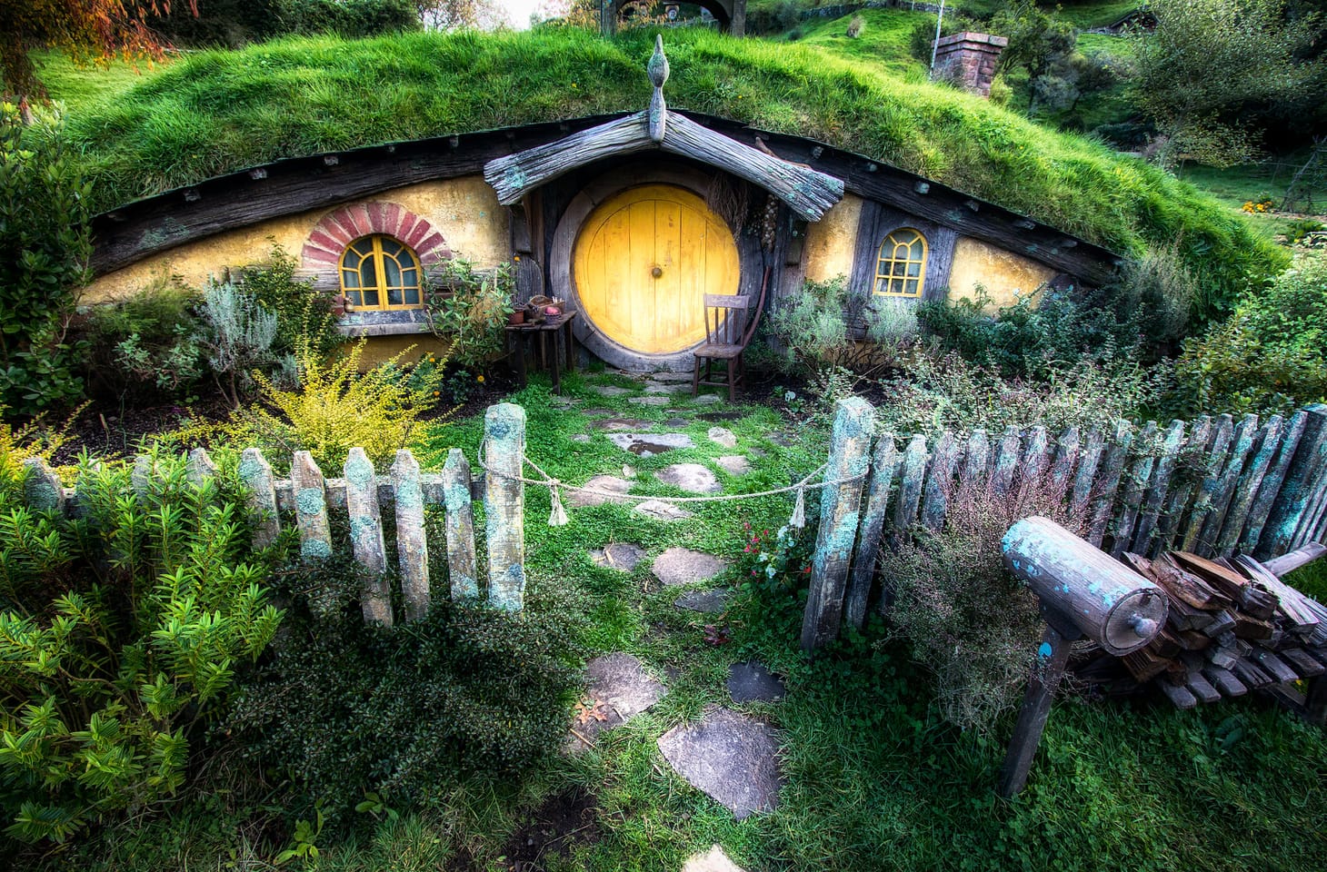 Illustration of a Hobbit house from The Lord of the Rings, glowing with warmth and overcome with vegetation. 